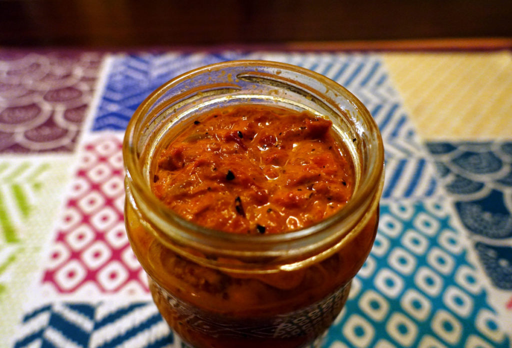 A brand-new jar of ajvar. There are bits of burnt pepper skin that was not completely peeled off. 