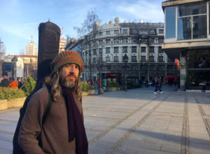 Christian Locke, 30, poses for a photo in Republic Square in Belgrade, Serbia. Locke was 33 when he left his home in Austin TX to pursue a woman he met on Facebook. Now, he lives in Belgrade and plays Yugoslav rock music. | Photo: Leah Willingham